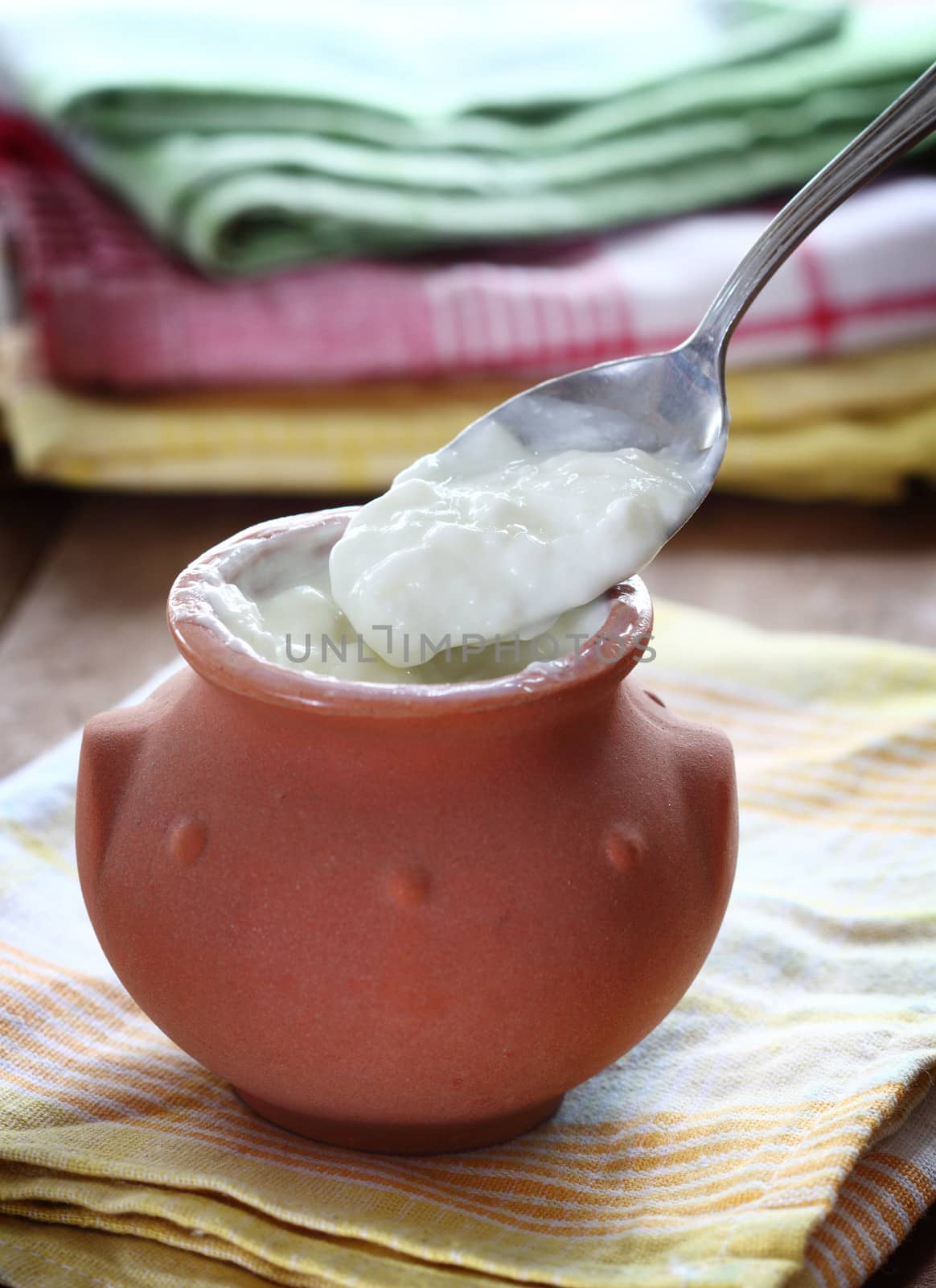 Homemade yogurt in a ceramic pot and spoon