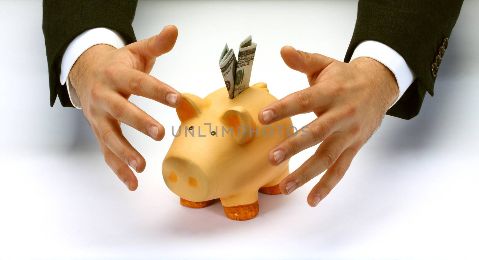 Businessman's hands  covering  piggy bank 