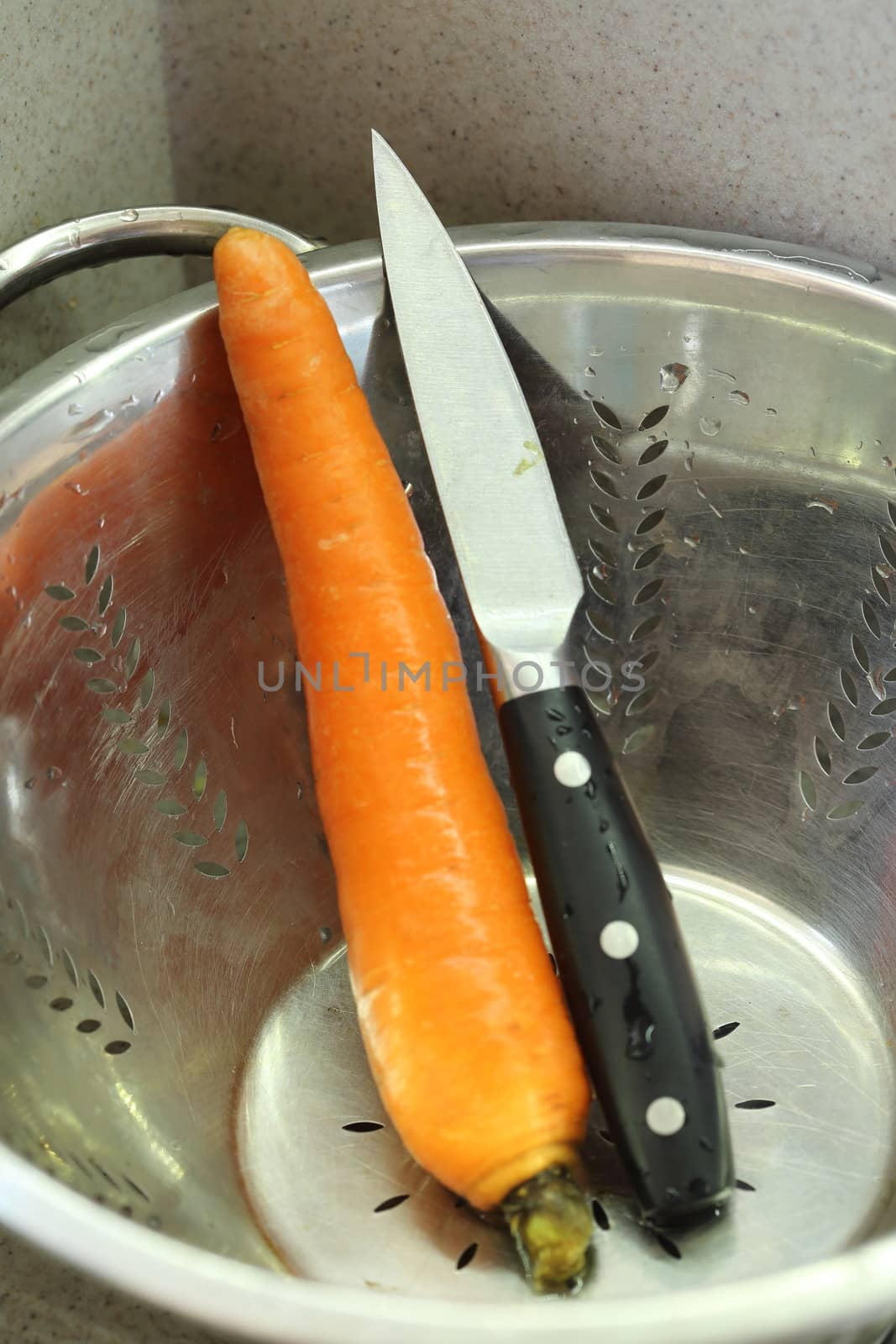 kitchen knife and carrot in a colander