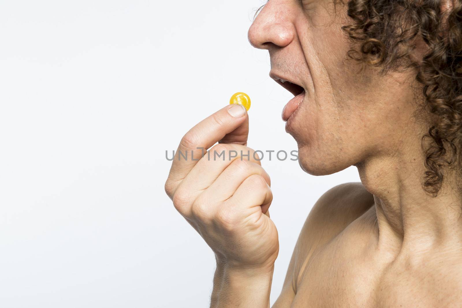 Cropped shot of bare chested mediterranean man taking colourful pill