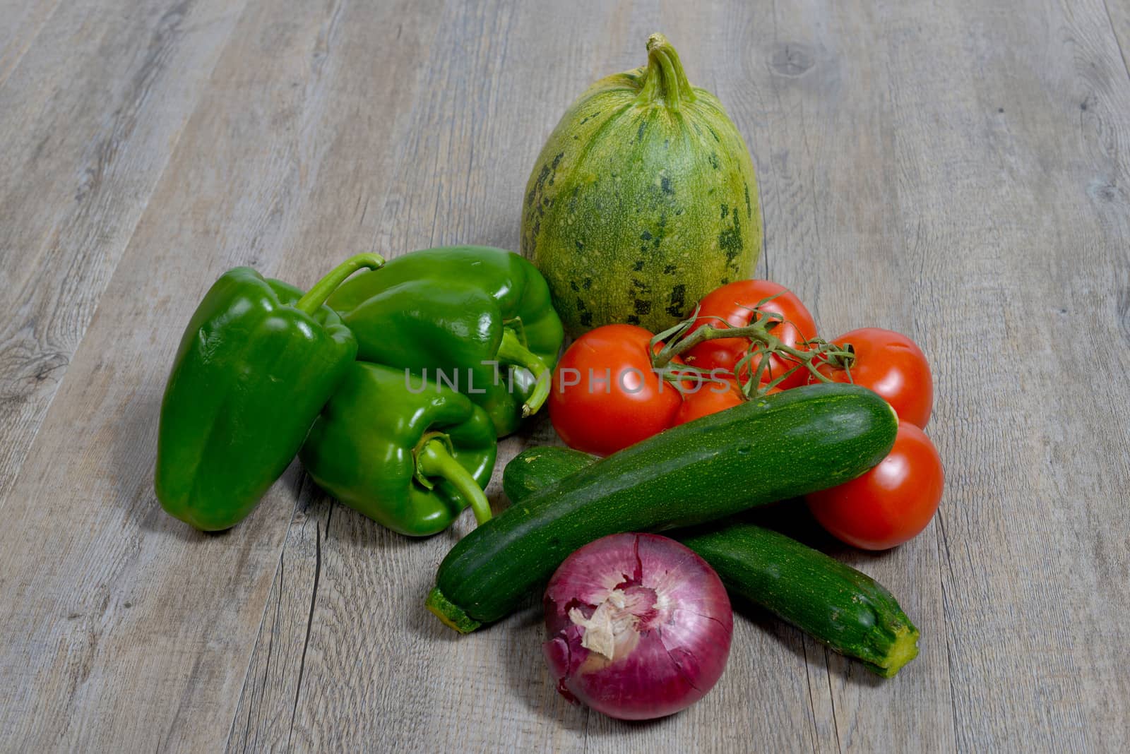 assortment of seasonal vegetables consisting of onions, zucchini, peppers, tomatoes and cucumber