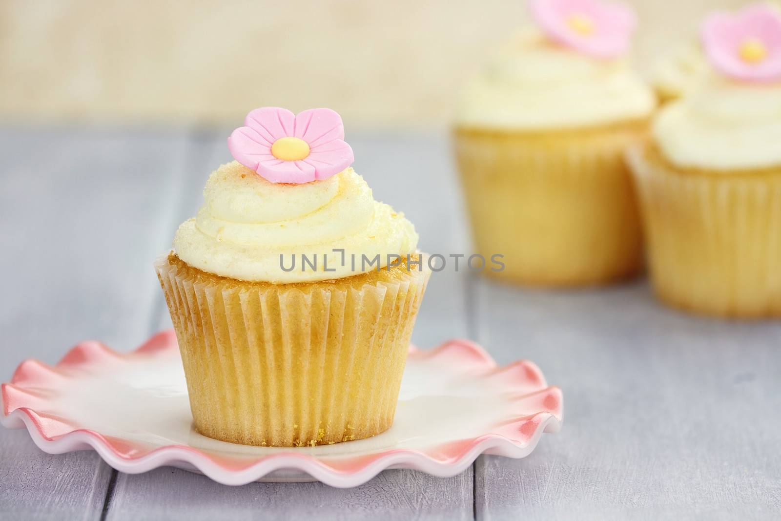 Pretty yellow and pink cupcakes with extreme shallow depth of field with antique dishes.