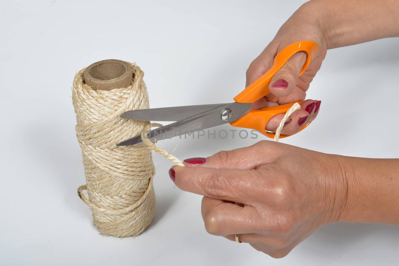 young woman cutting a piece of string by philipimage