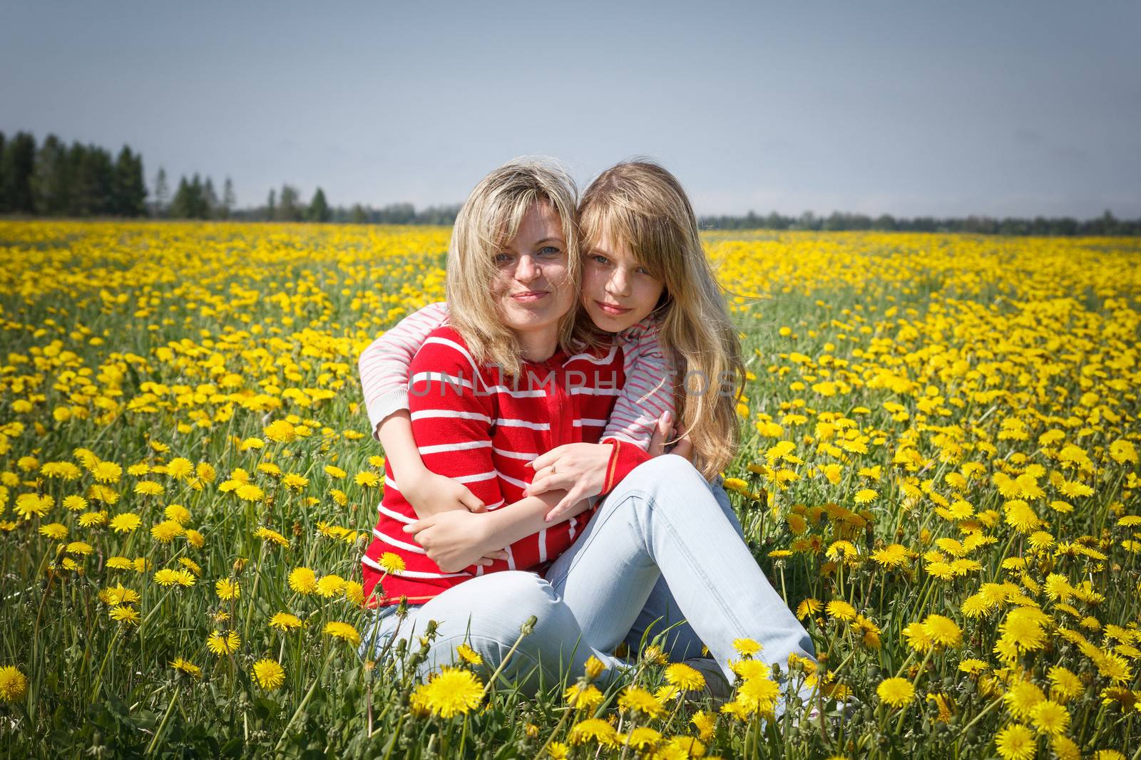 mother with daughter in dandelion field