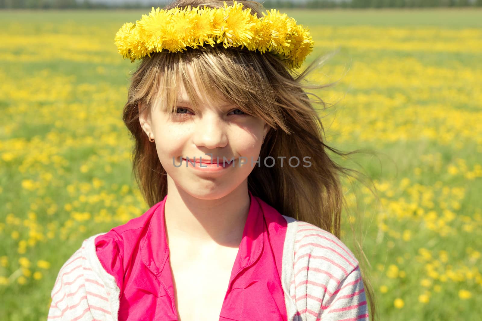 young girl with dandelion wreath in meadow