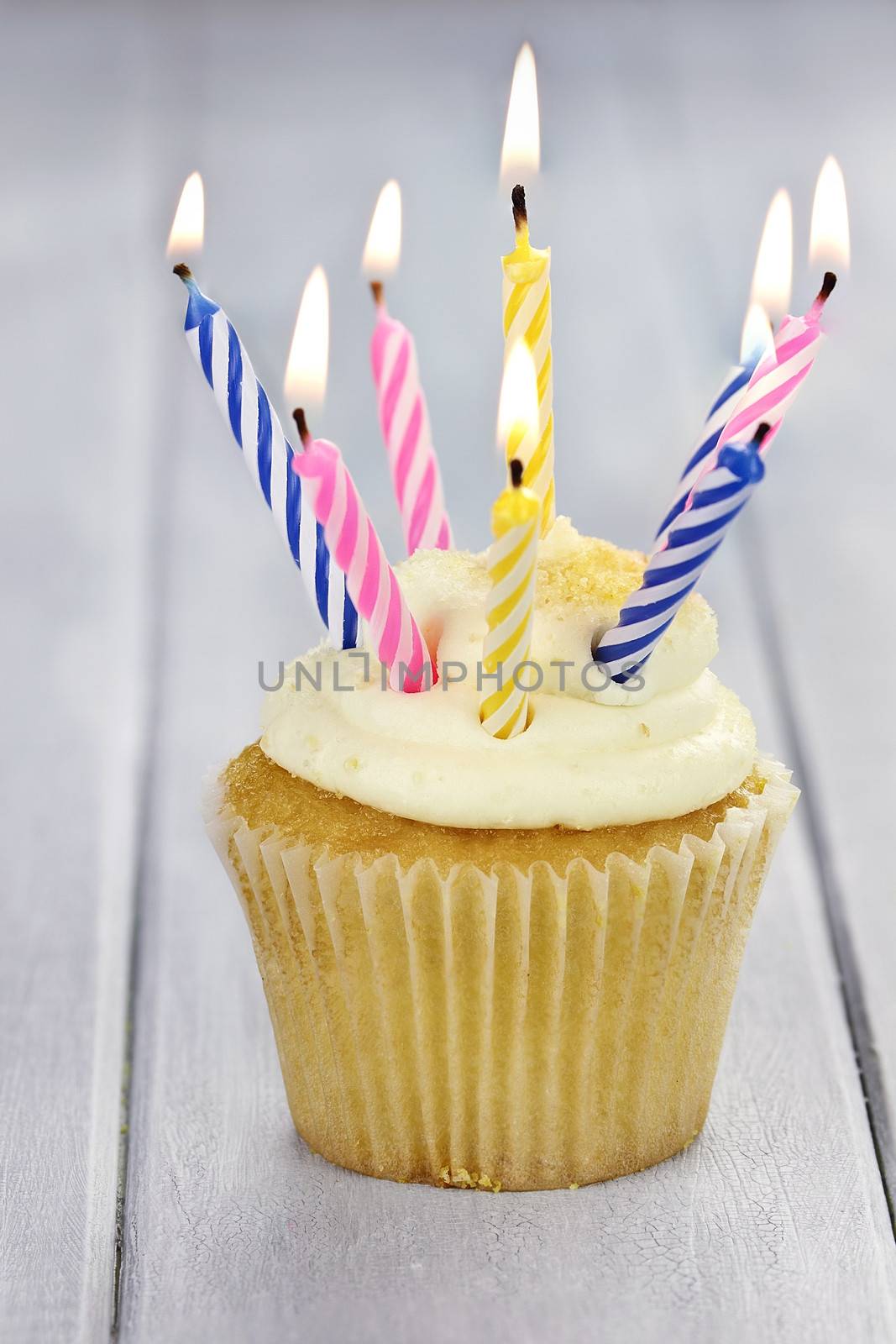 Cupcake with eight burning candles and copy space. Shallow depth of field.