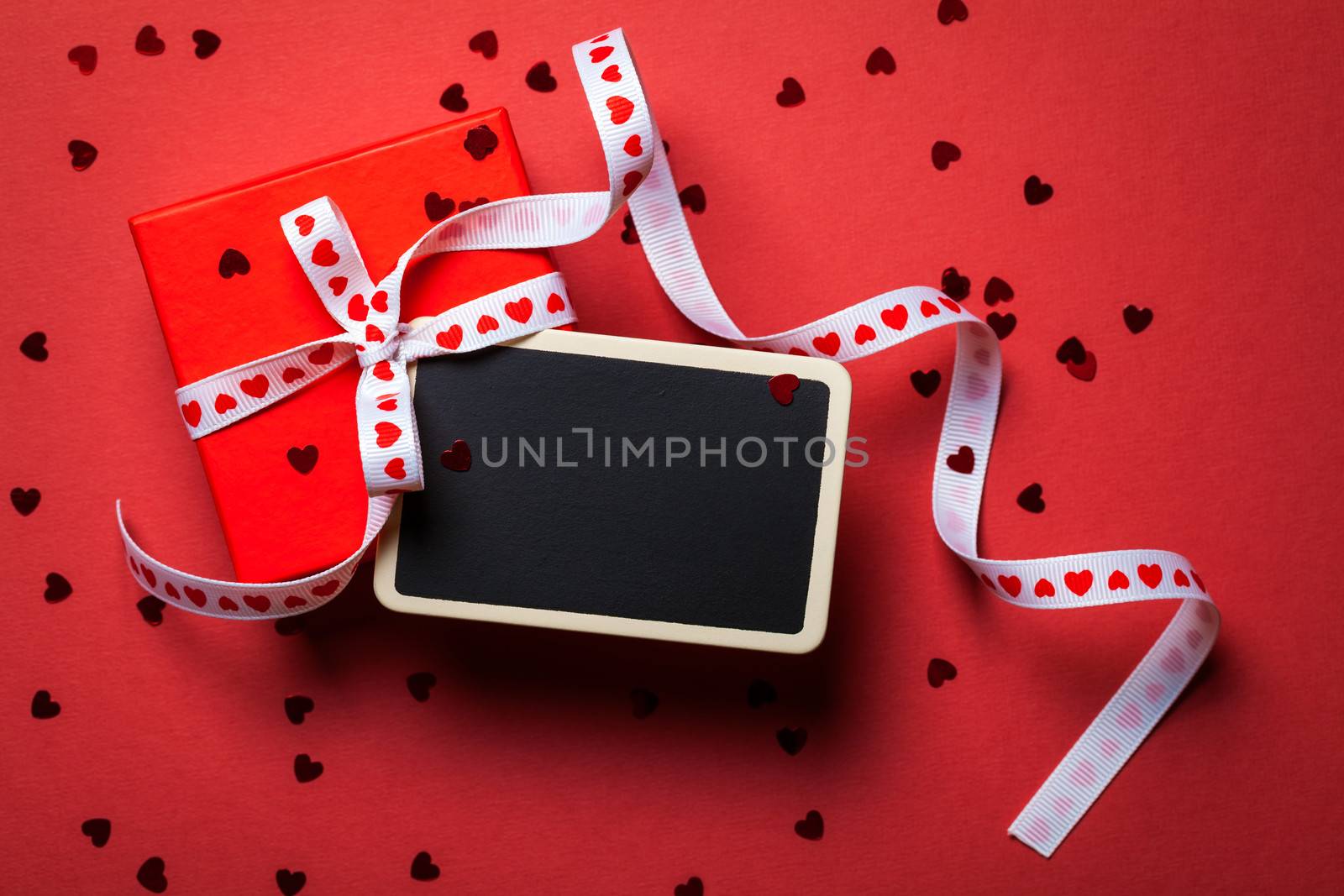 Gift box with framed blackboard on red paper background. Valentines Day . Top view