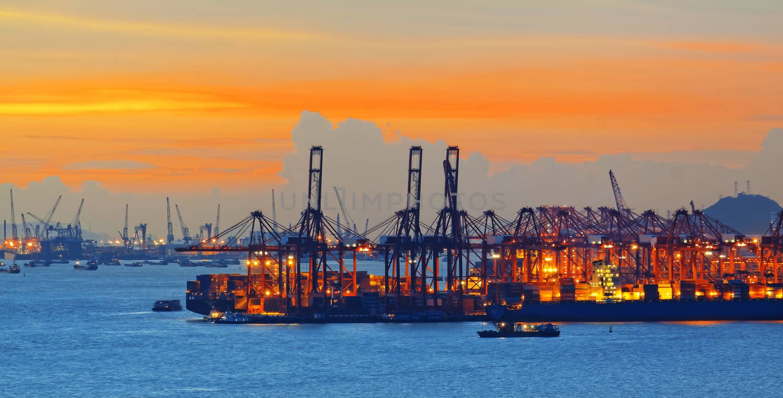 Silhouette of several cranes in a harbor, shot during sunset.