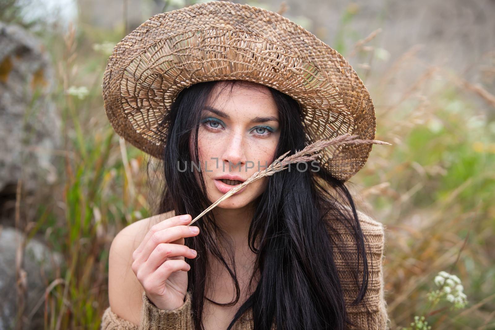 Portrait of a girl in straw hat against soft nature background