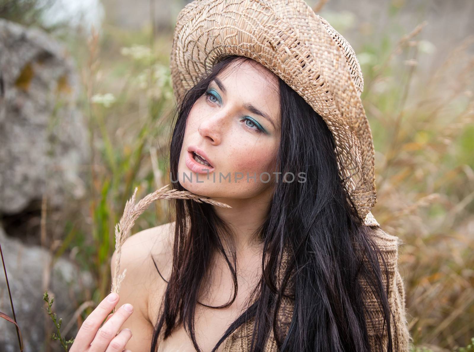 Portrait of a girl in straw hat against soft nature background