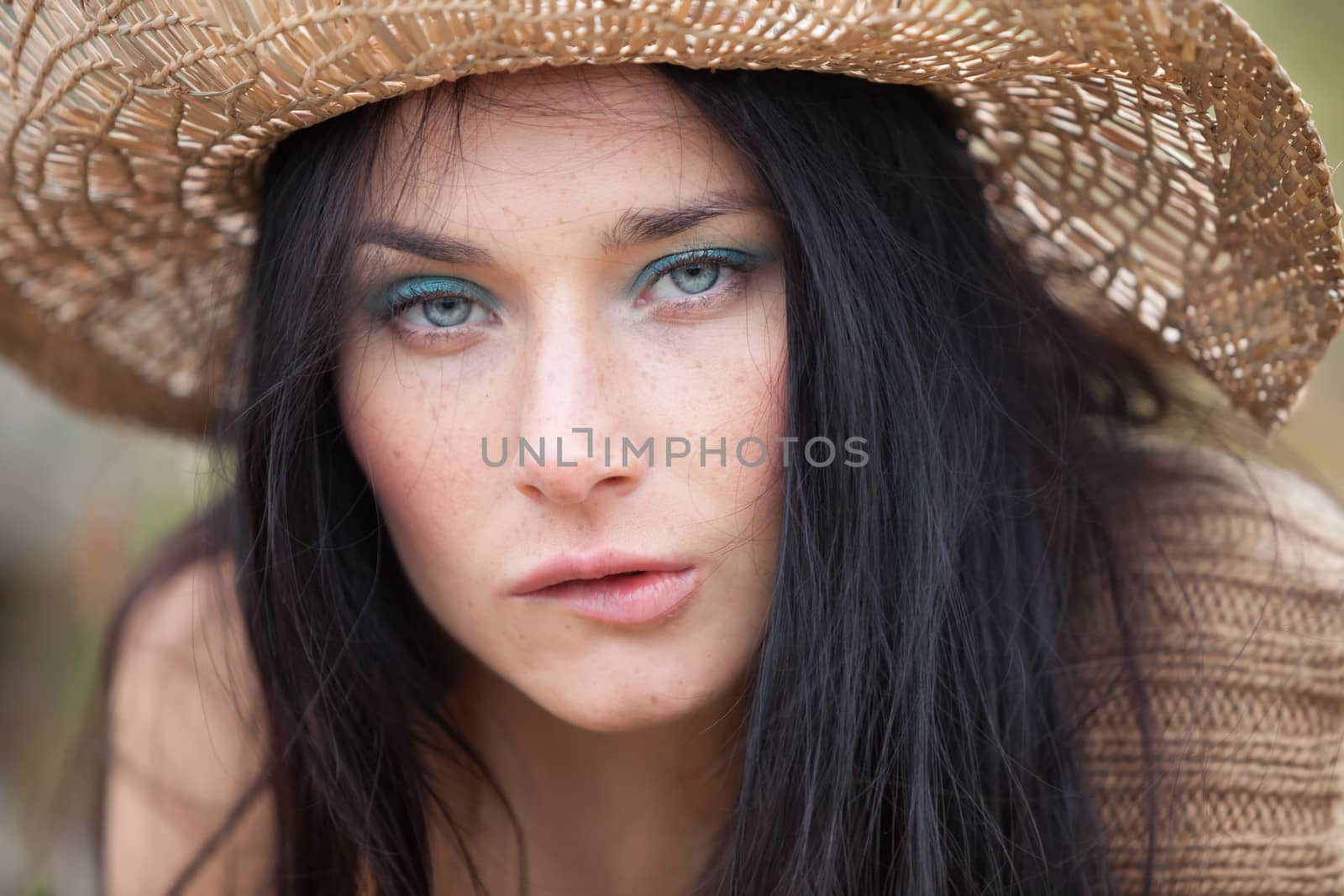 Portrait of a girl in straw hat against soft nature background