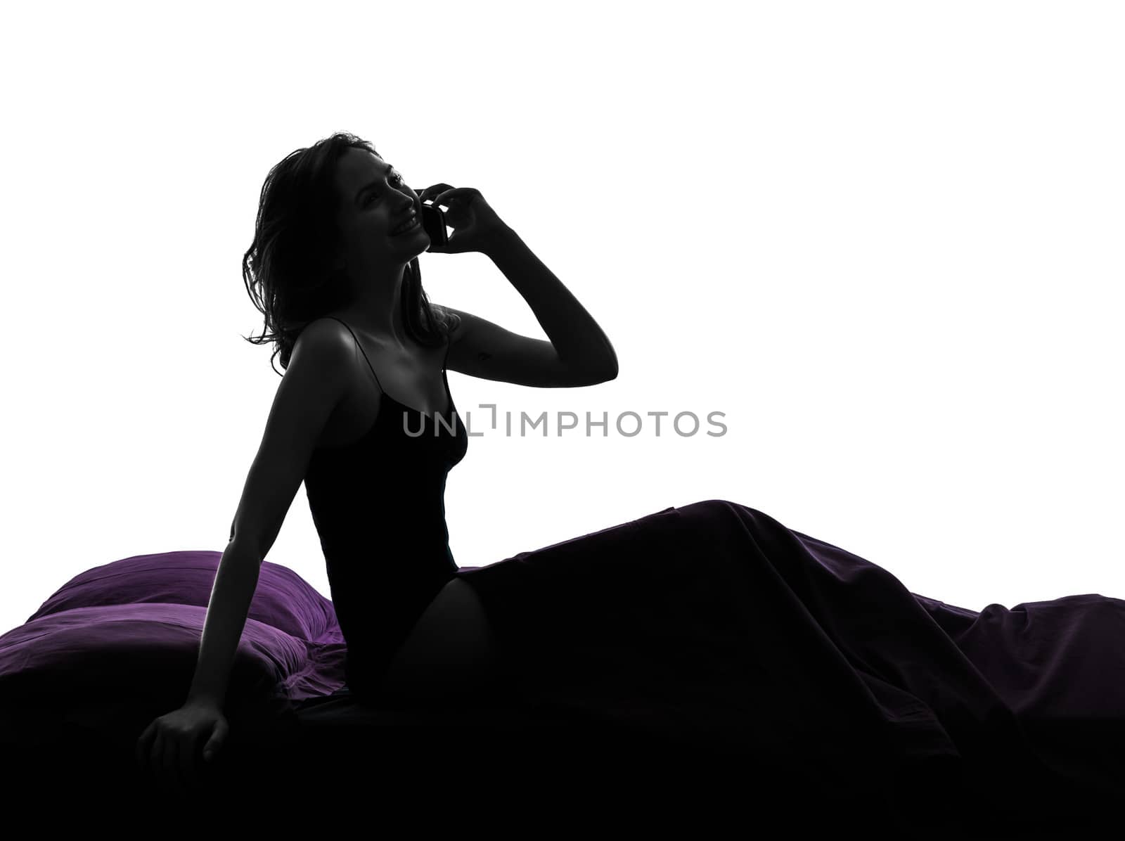 one woman happy on the telephone in bed silhouette studio on white background