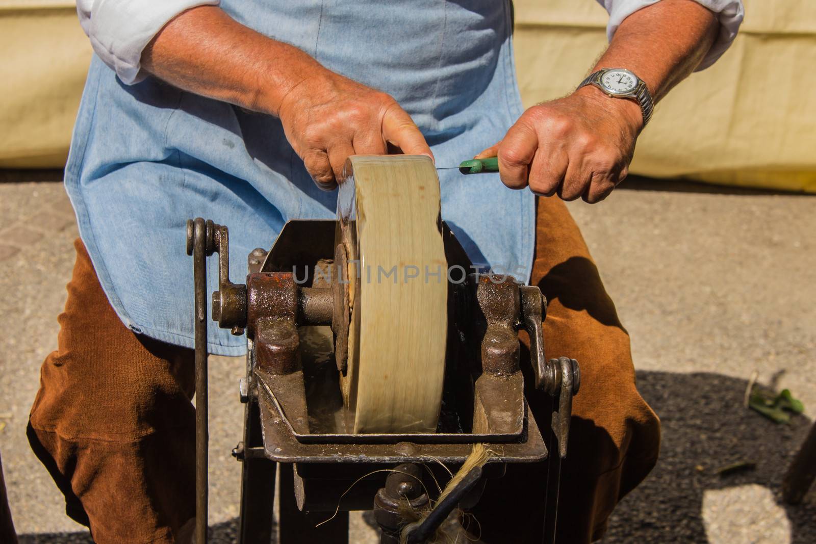 A man hones knives in front of a busy street