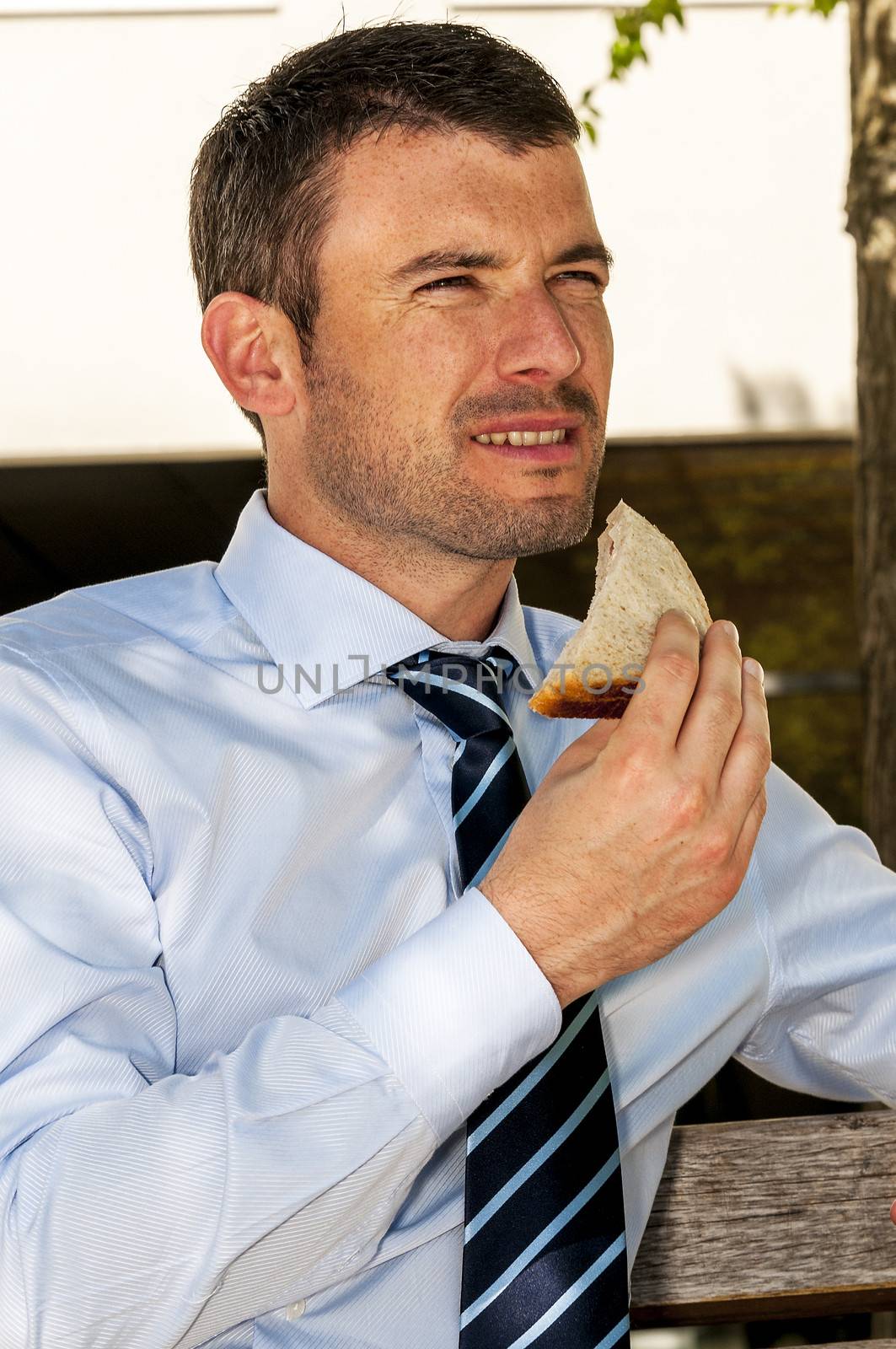 attractive businessman is eating a sandwich