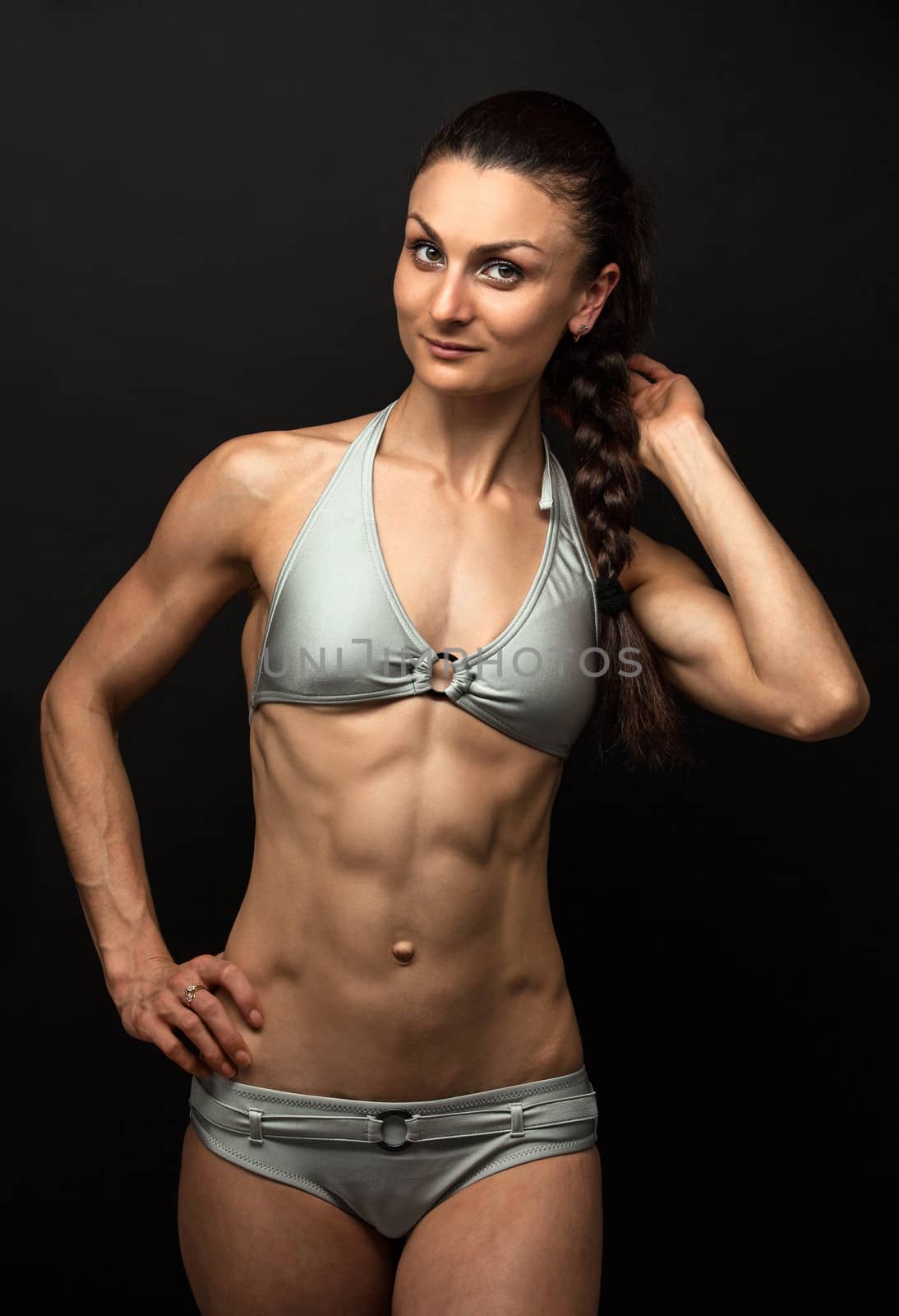 Young fitness woman posing over black background