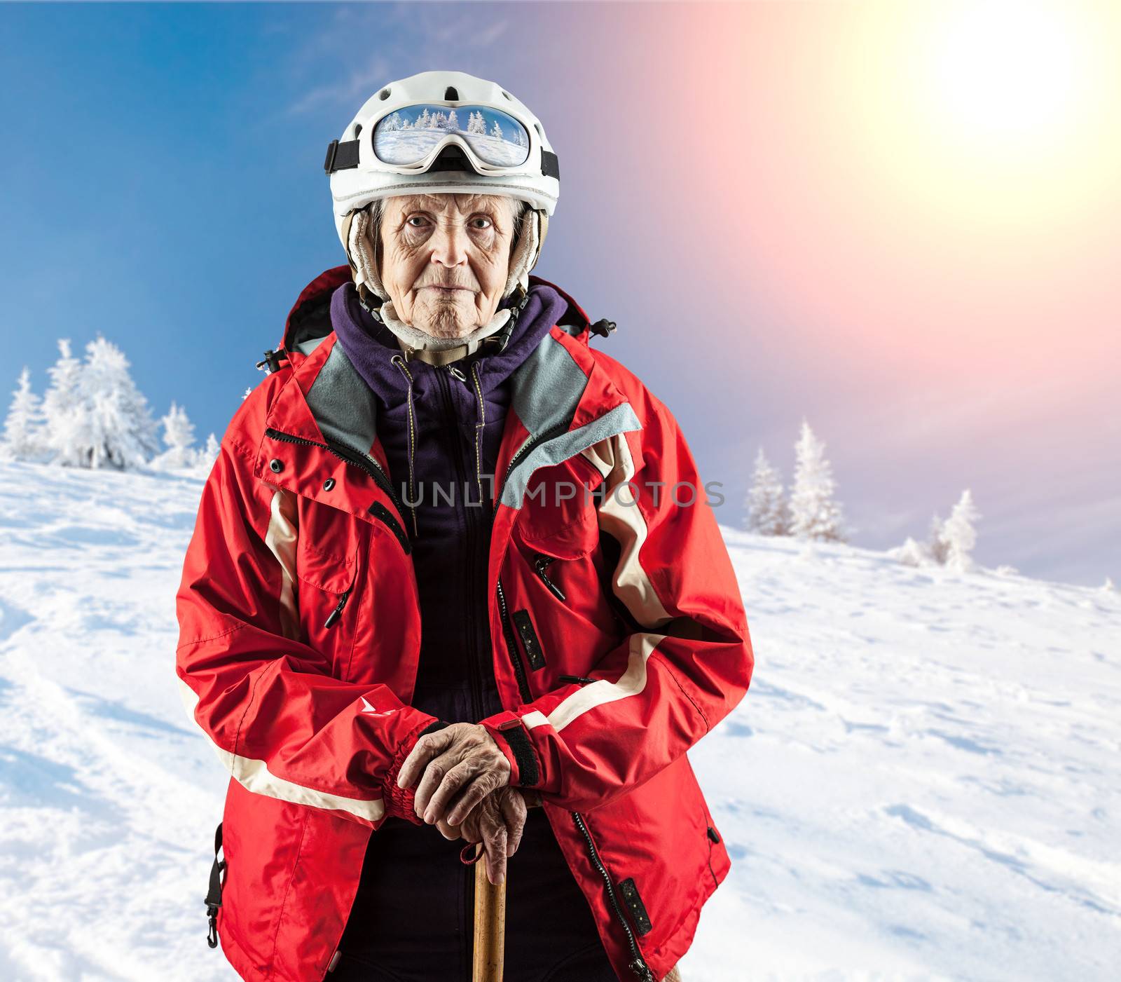 Old woman standing in winter ski goggles on snow holiday in mountains. With clipping path.