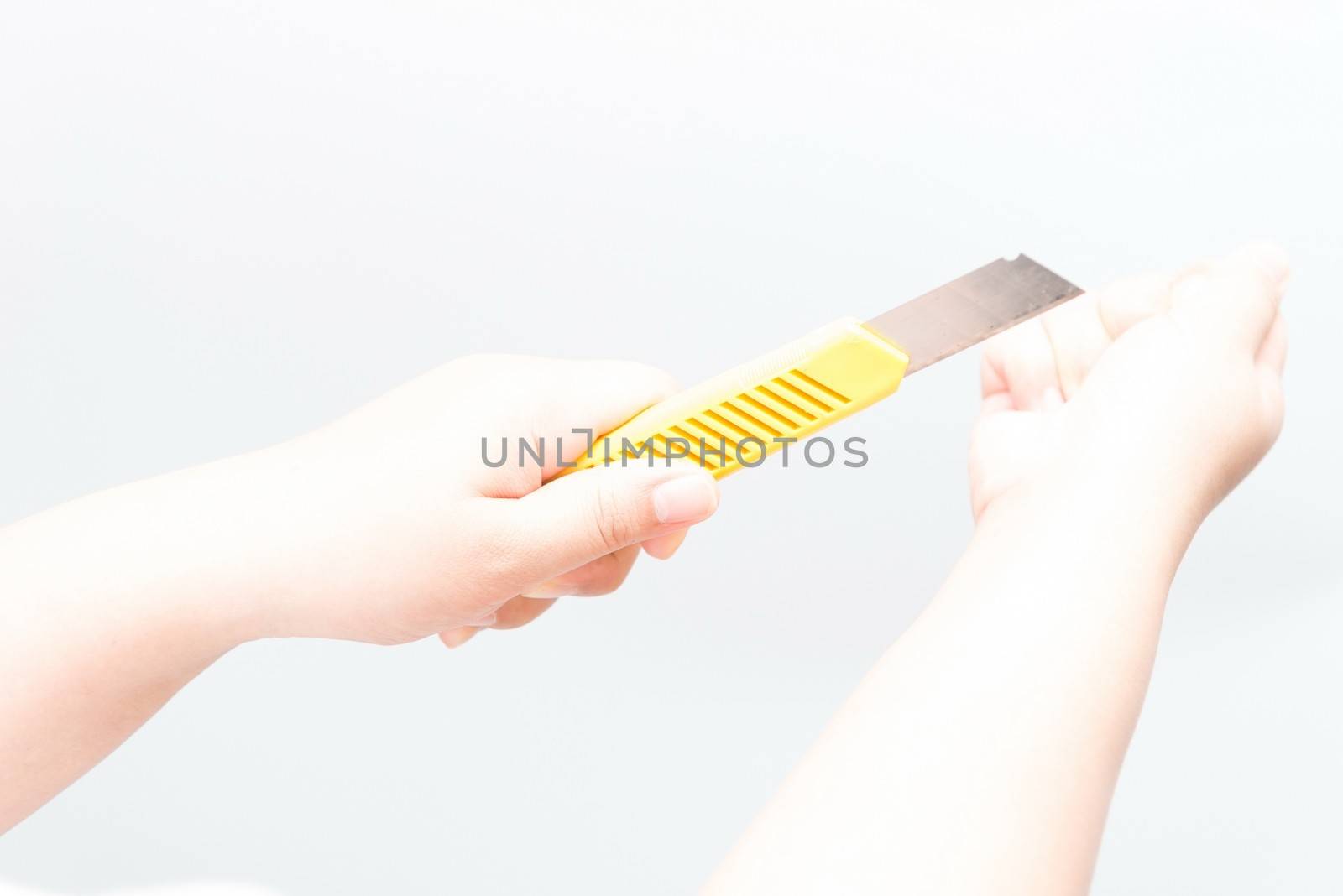 Asian woman holding a yellow box cutter knife trying to kill herself, isolated