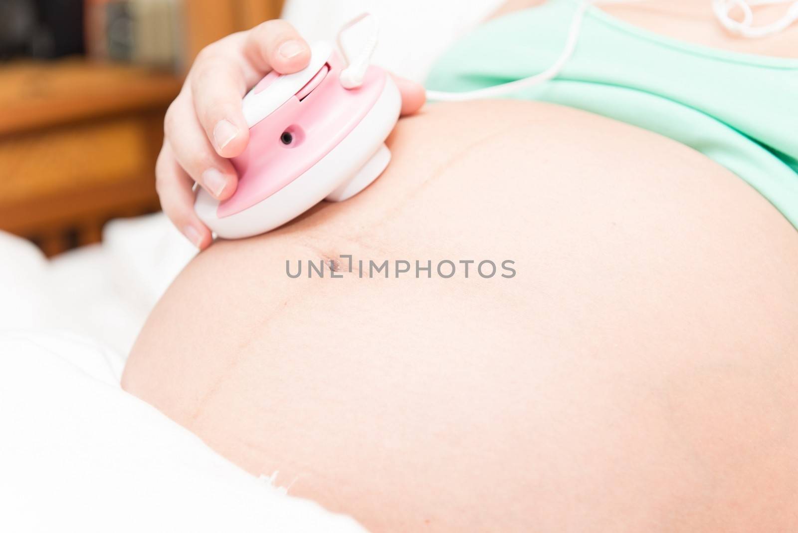 Young thai pregnant woman listening to baby using a listening device