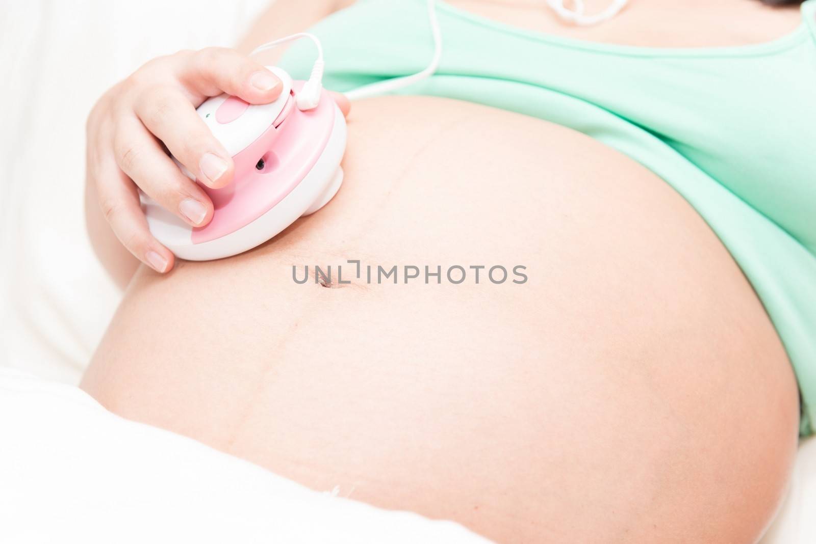 Young thai pregnant woman listening to baby using a listening device