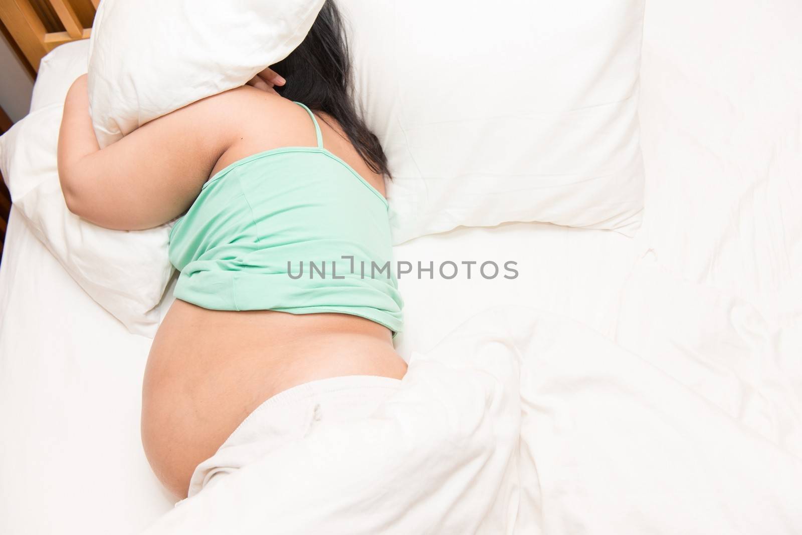 Young Thai pregnant woman sleeping in bed, taken in door