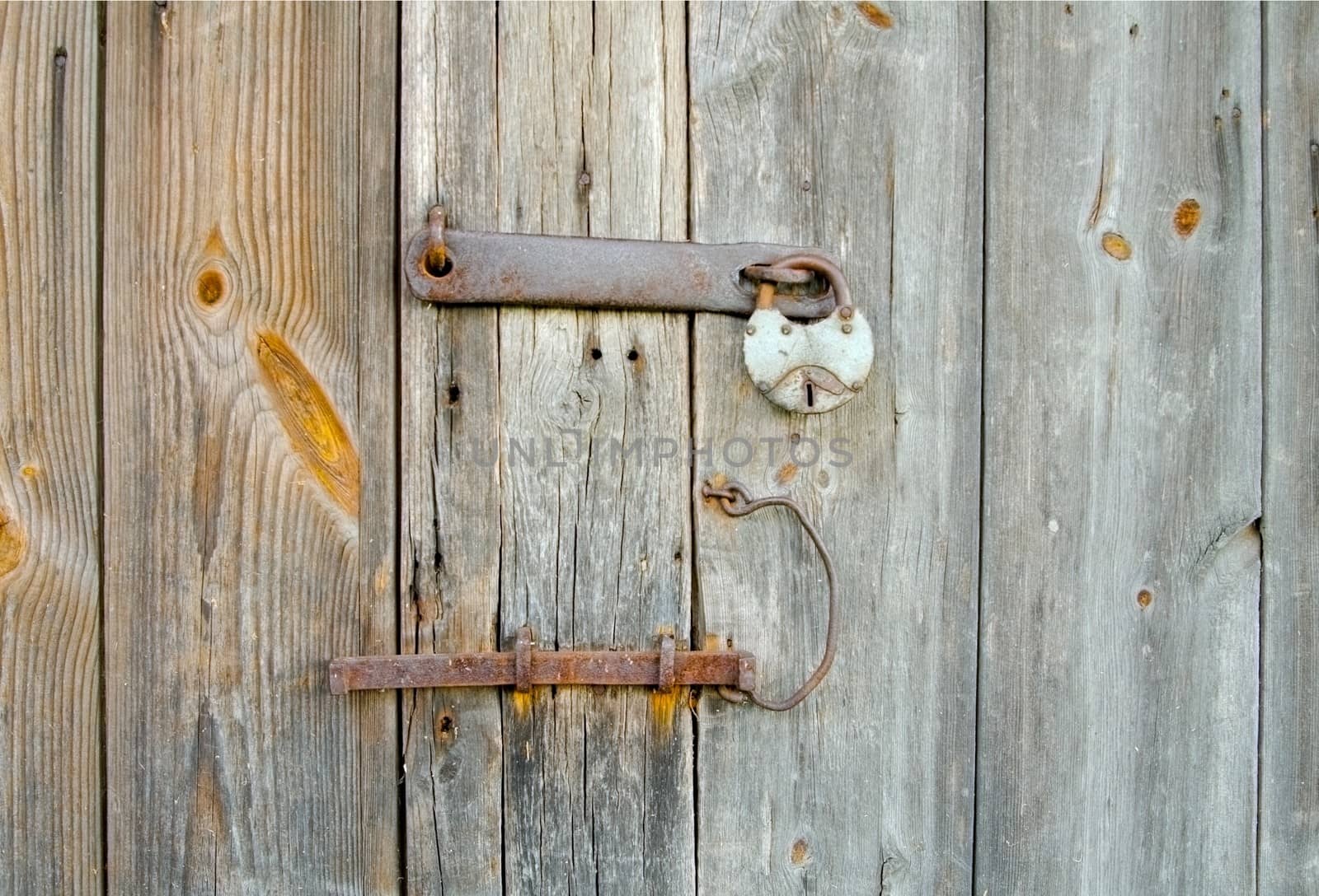 Wooden door with a rusty bolt and padlock by Stabivalen