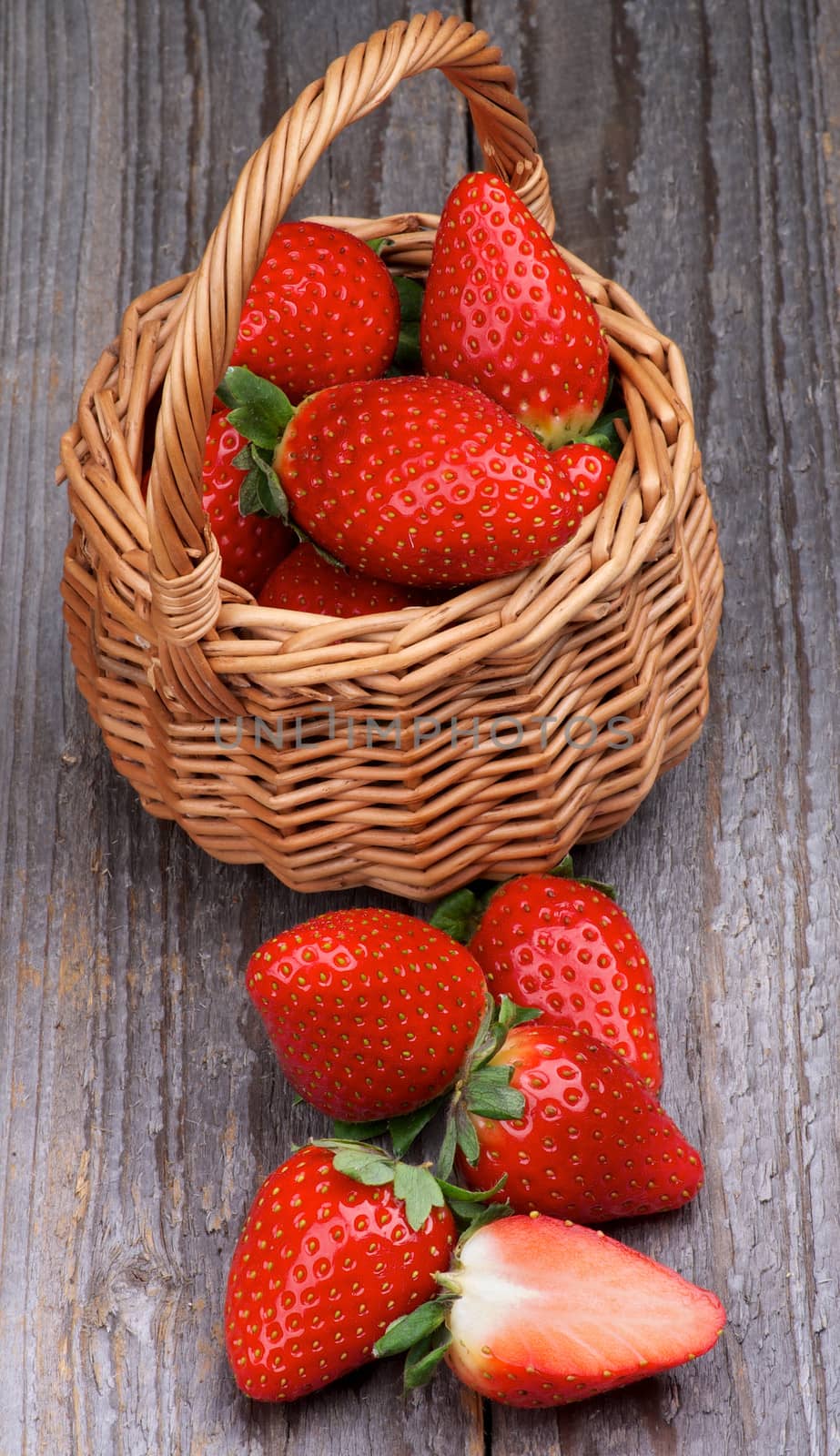 Fresh Ripe Strawberries in Wicker Basket closeup on Rustic Wooden background