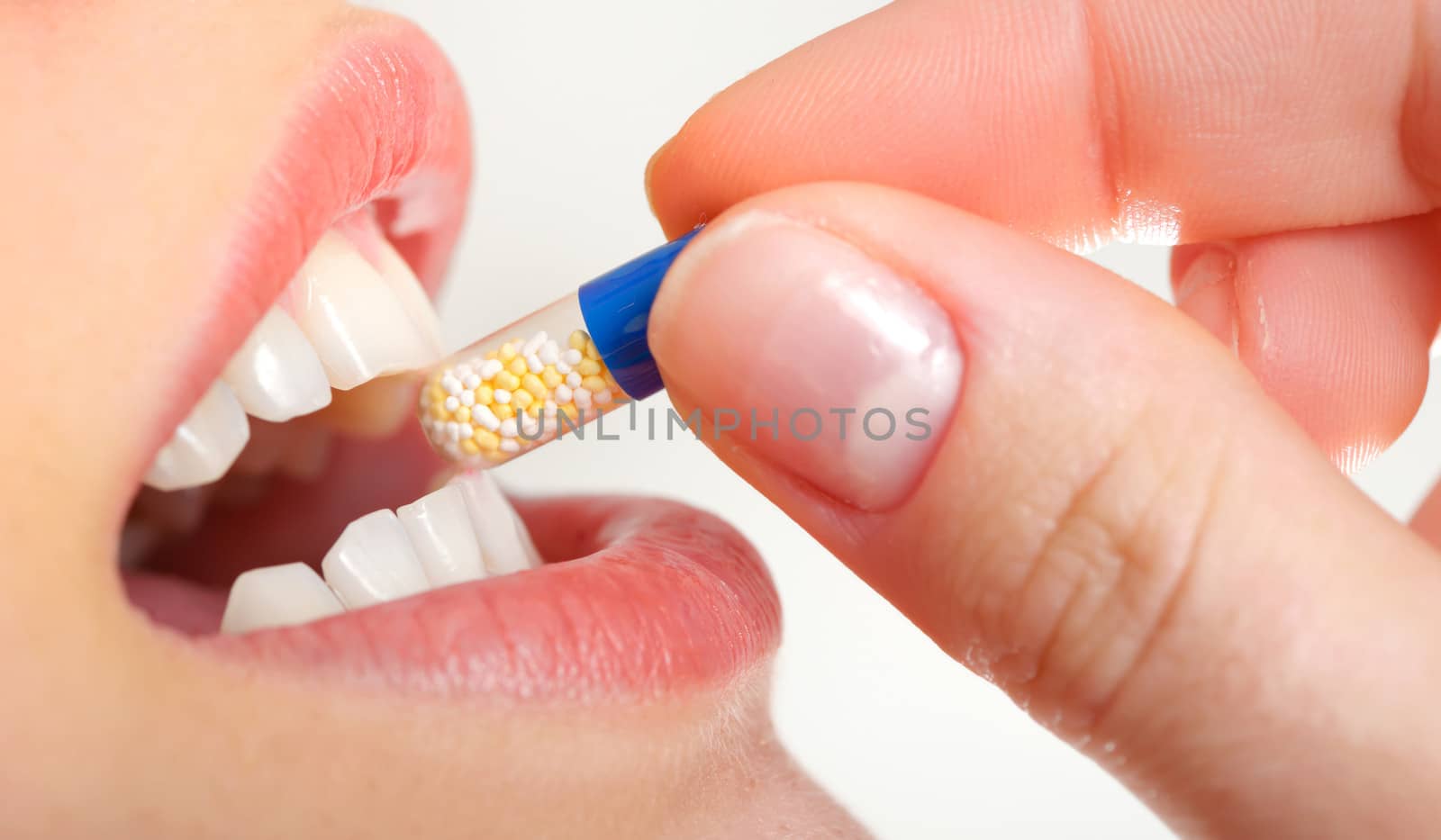 young woman holding pill by her mouth