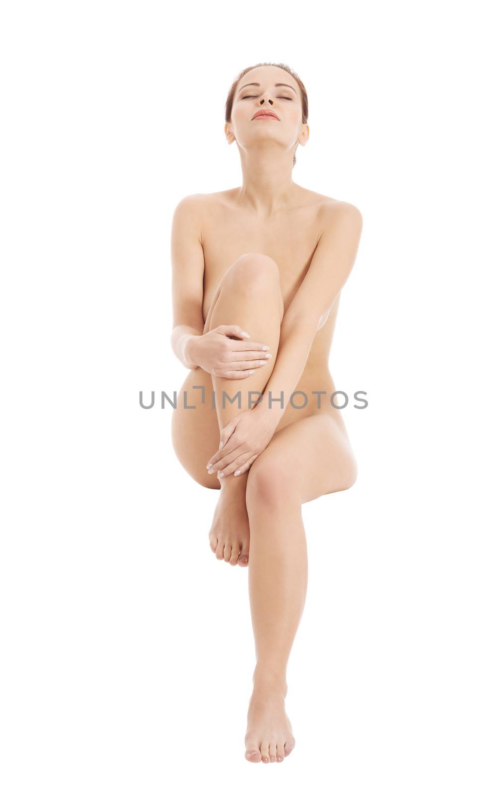 Young beautiful naked woman sitting with one leg up. Isolated on white.