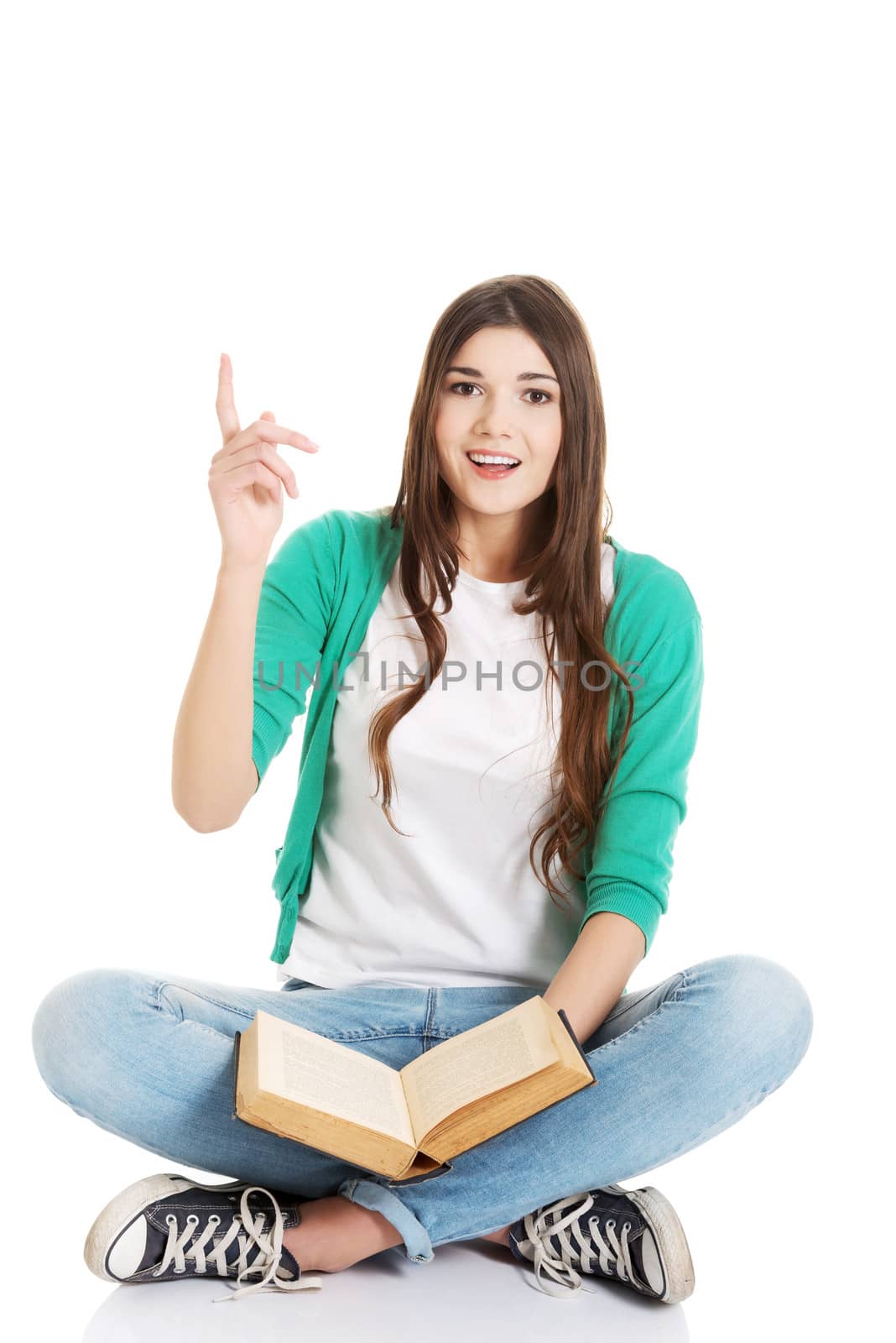 Young beautiful woman student sitting with book and pointing up. by BDS