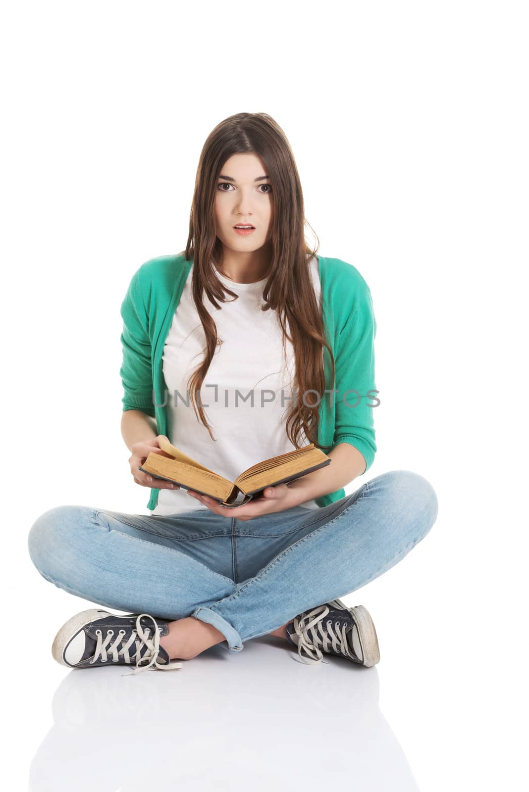 Young woman student sitting and reading a book. Isolated on white.