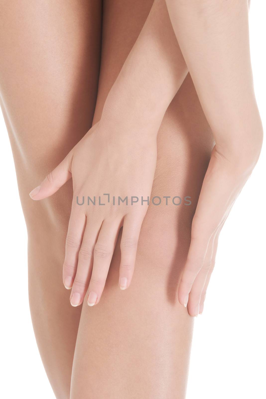 Close up on beautiful woman's smooth knees with hands. Over white background.