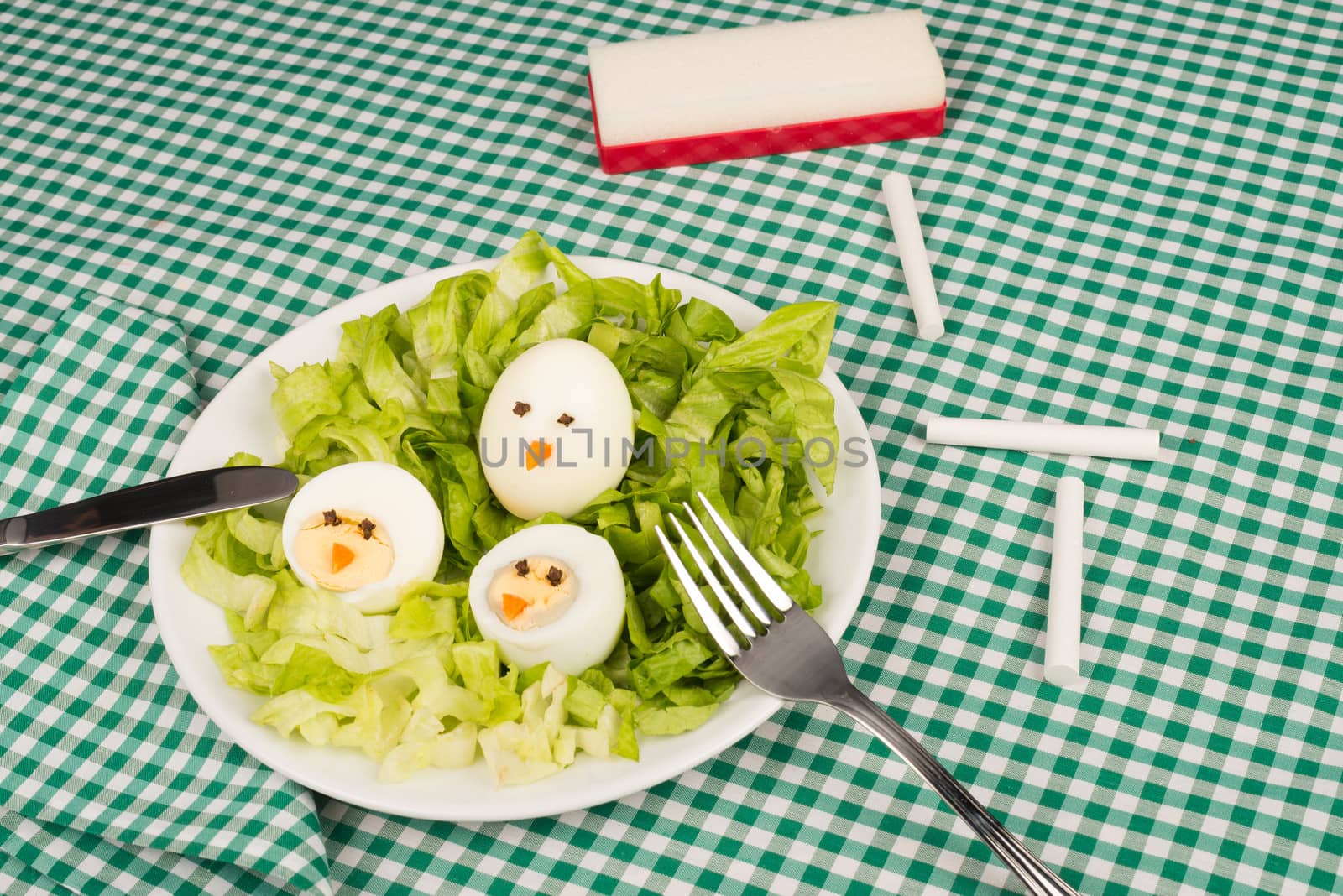 A salad served with decorated eggs, a kid meal