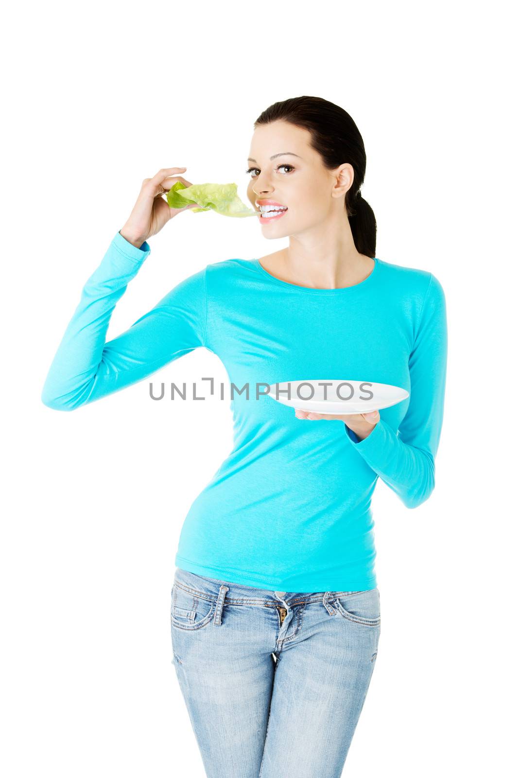 Young beautiful woman eatting lettuce leaf. Isolated on white.