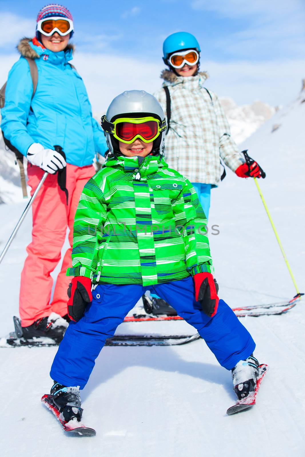 Ski, winter, snow, skiers, sun and fun - family enjoying winter vacations. Little boy with his mother and sister.