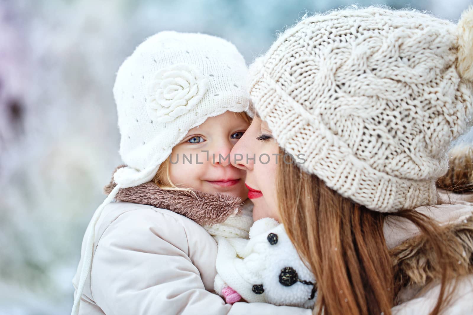 Mother holds daughter on hands in winter forest by Vagengeym