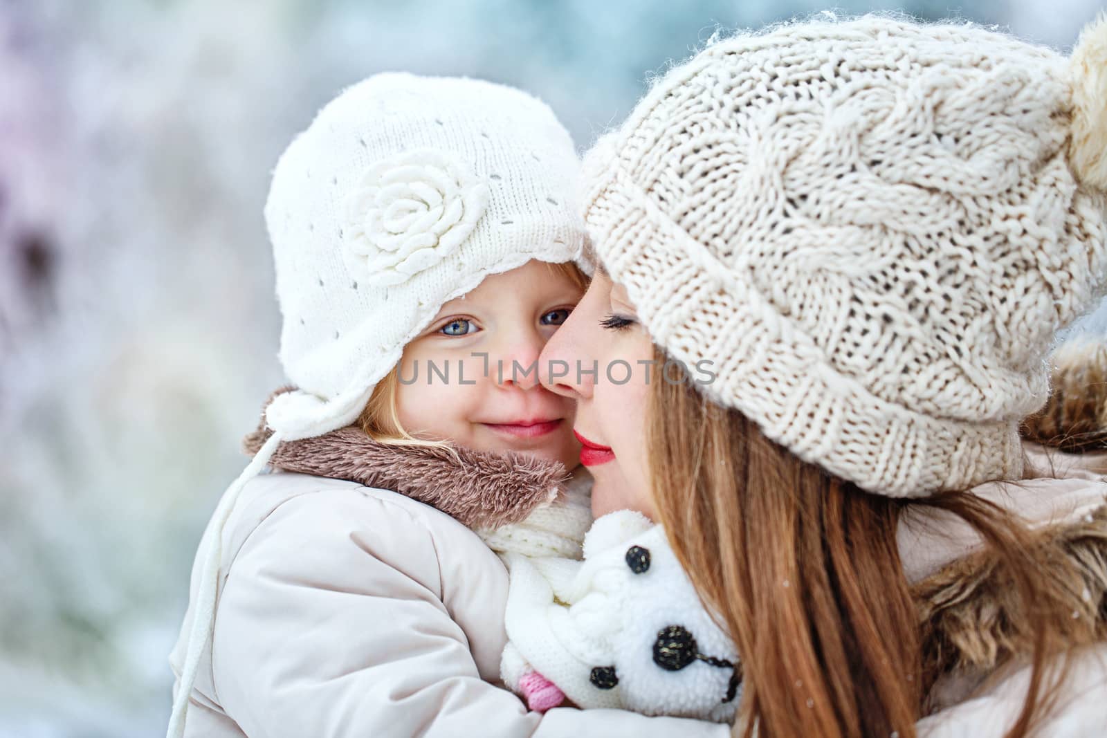 Young mother holding a daughter in a winter forest for a walk