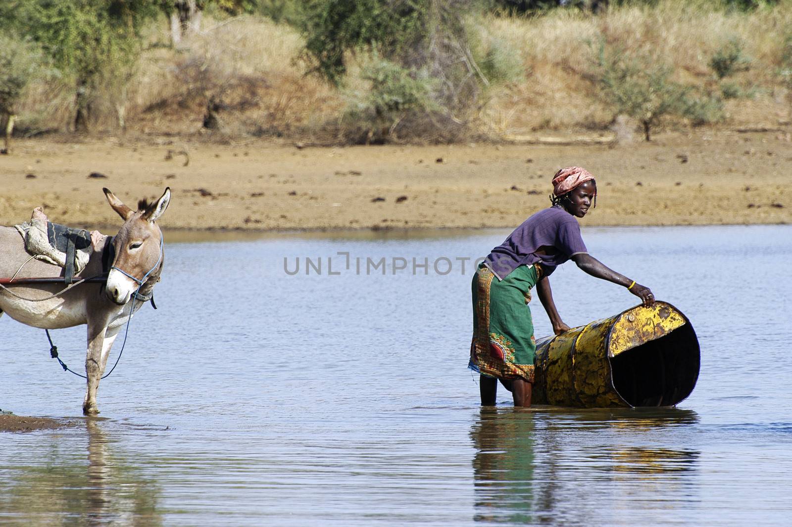 filling and transportation of water bottles at lake is for women to irrigate crops