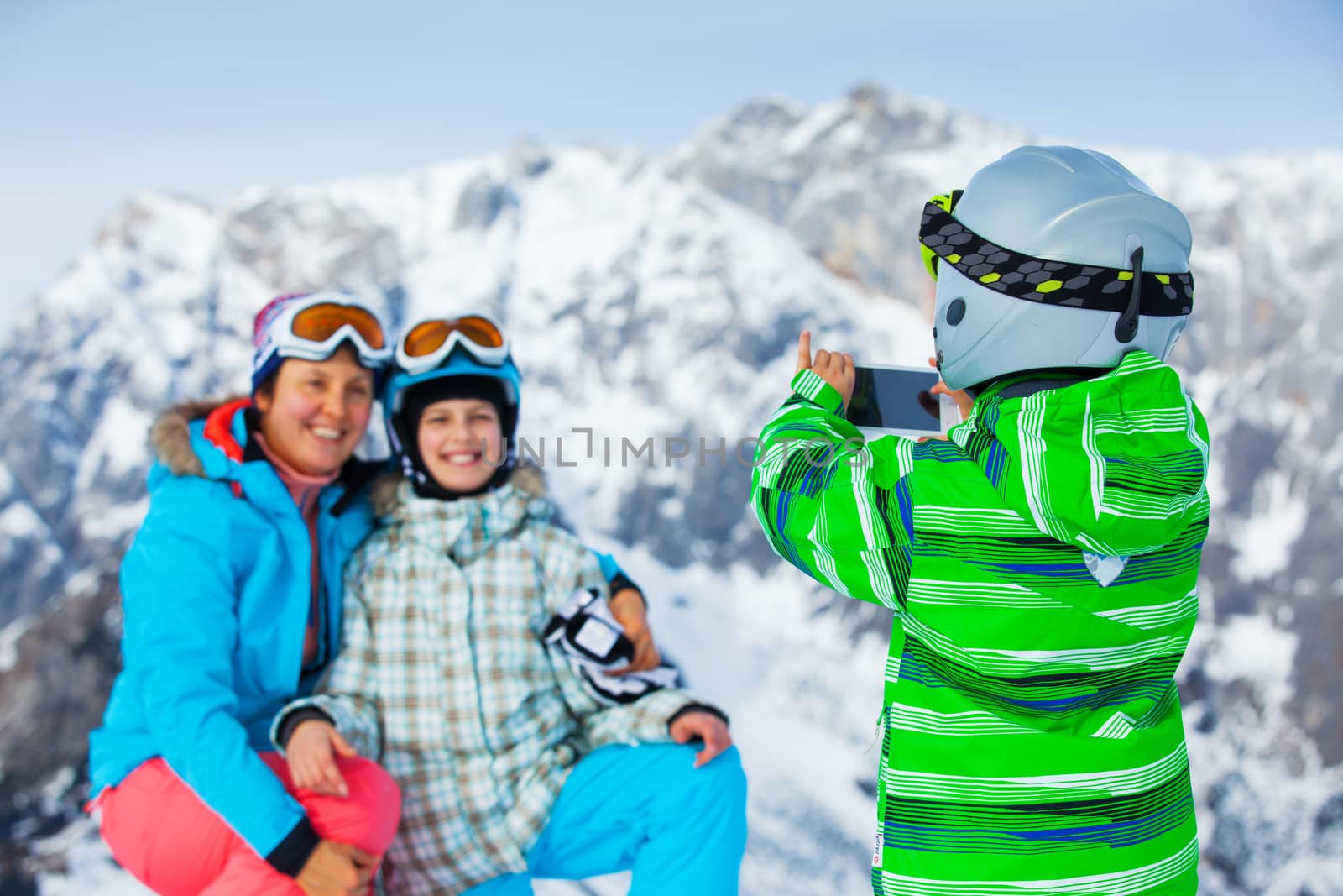 Ski, winter, snow, skiers, sun and fun - boy photographed family on phone during winter vacations.