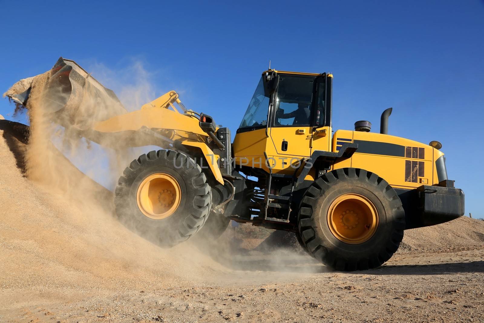 Bulldozer dumping stone and sand in a mining quarry