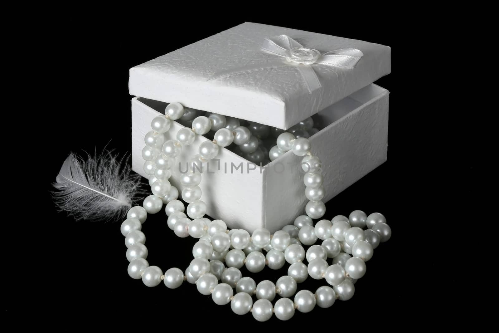 Gift box with string of white pearls and a white feather