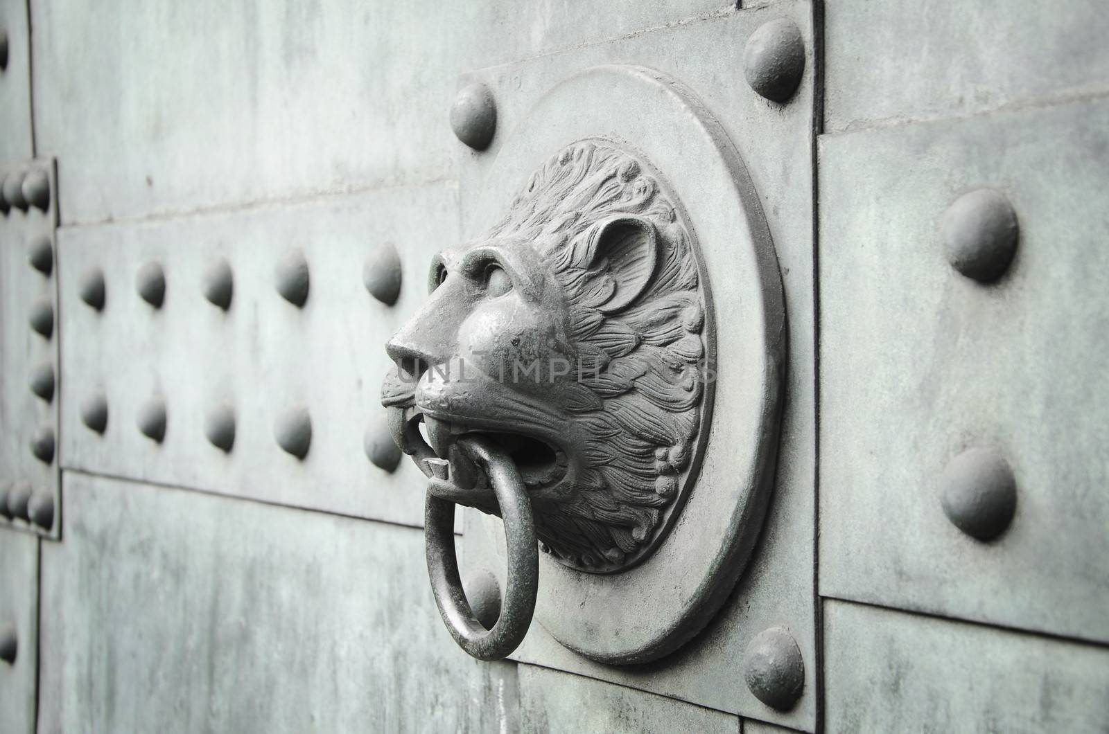 horizontally oriented photo of a lion head shaped ancient door knocker