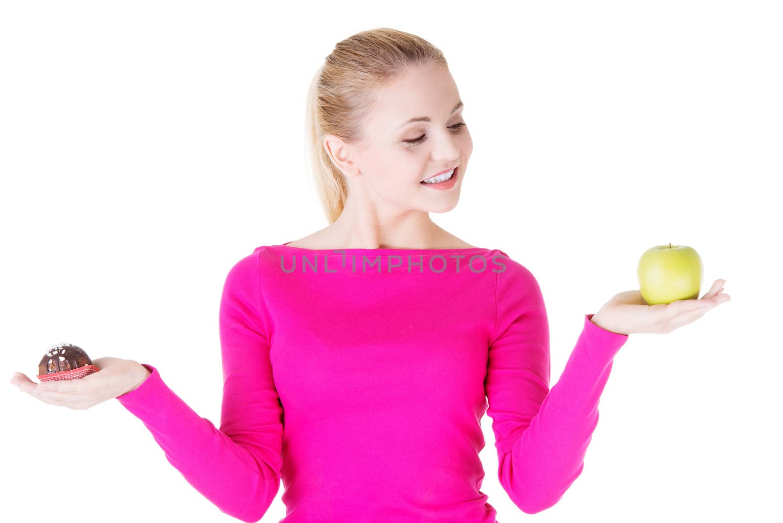 Young casual woman holding an apple and cookie. Isolated on white.
