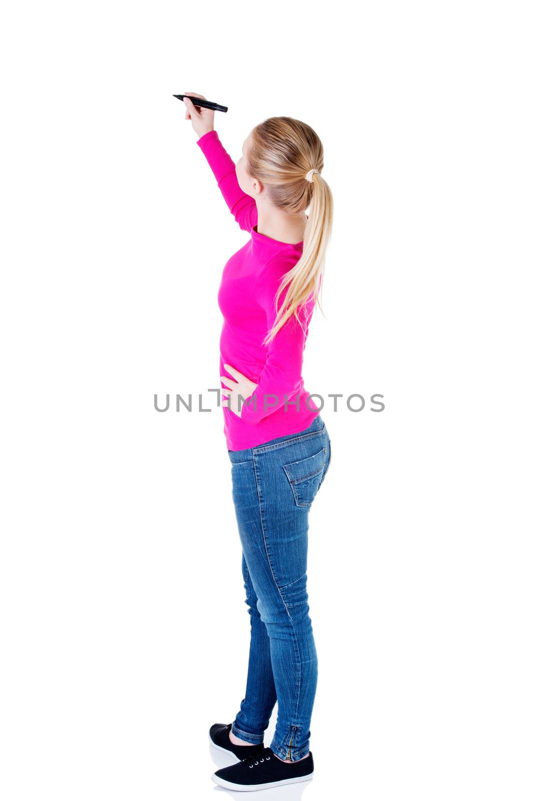 Young casual woman writing on copy space. Back view. Isolated on white.