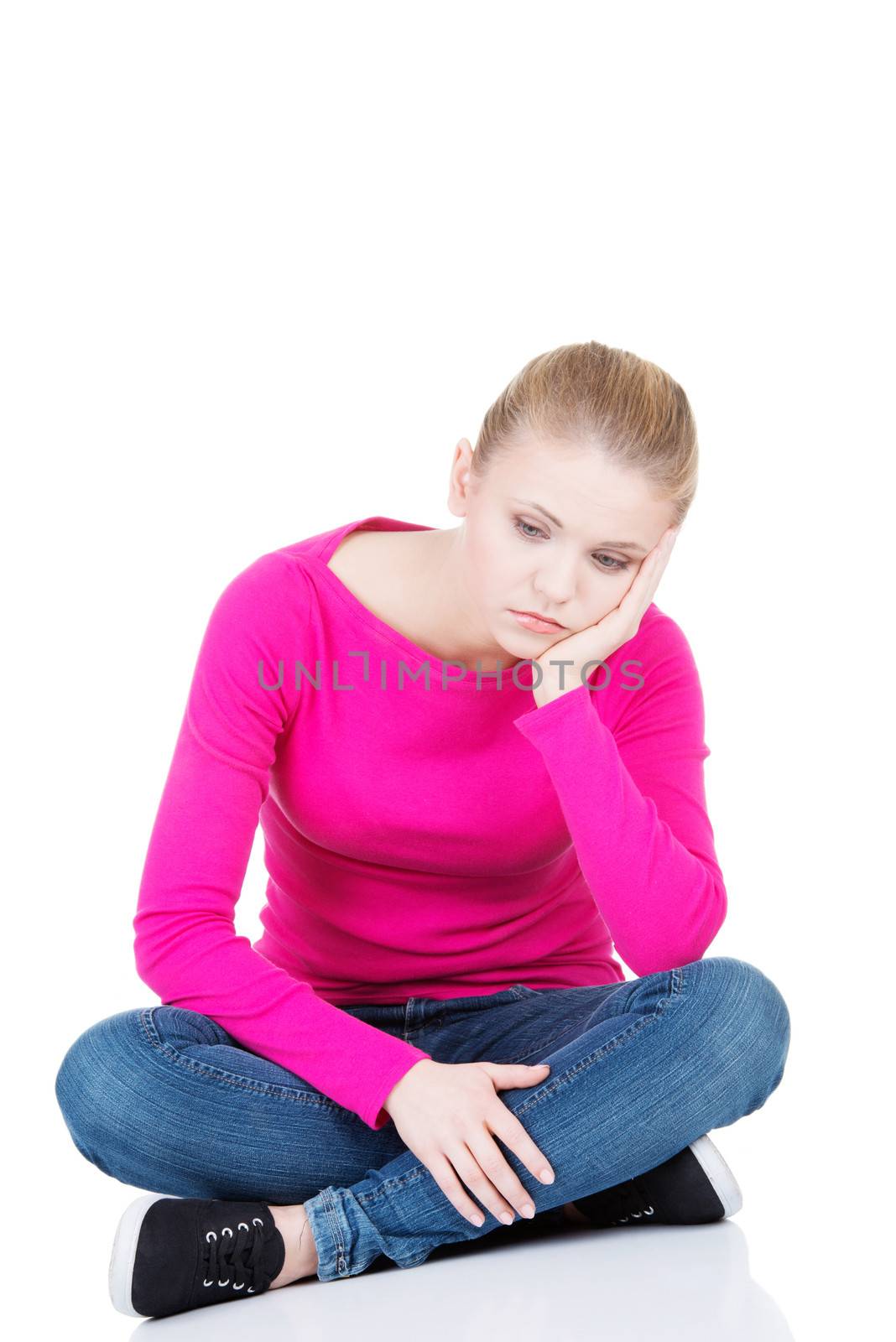 Young sad woman sitting. Isolated on white.