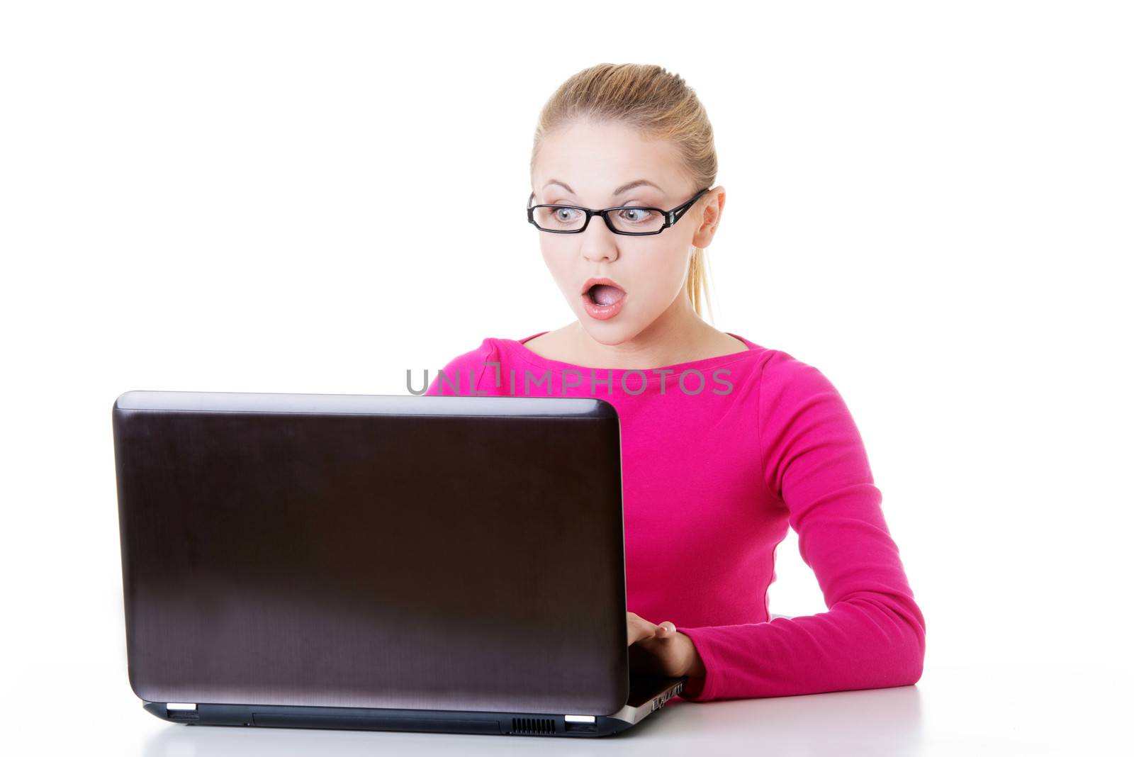 Young surprised woman sitting in front of laptop. Isolaed on white.