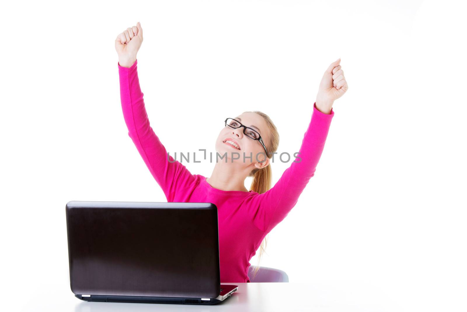 Young happy woman sitting in front of laptop. Isolated on white.