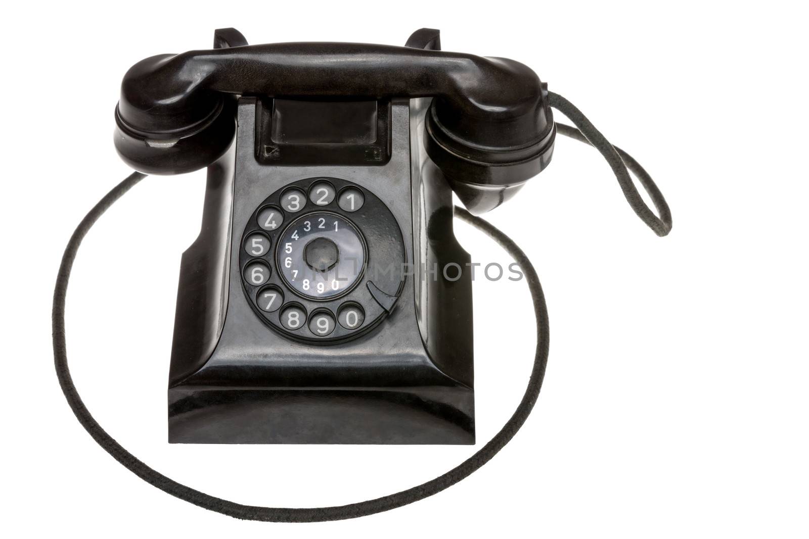 Classic old black rotary dial-up telephone instrument, closeup frontal view with the handset in place over a white studio background