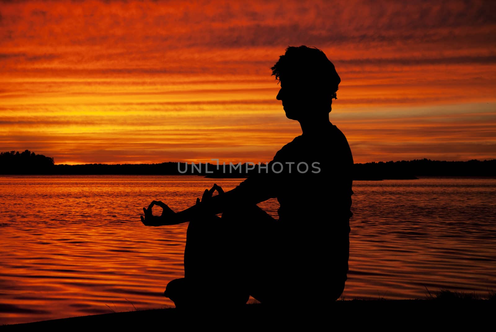 Silhouette woman sitting and relaxing against orange sunset 