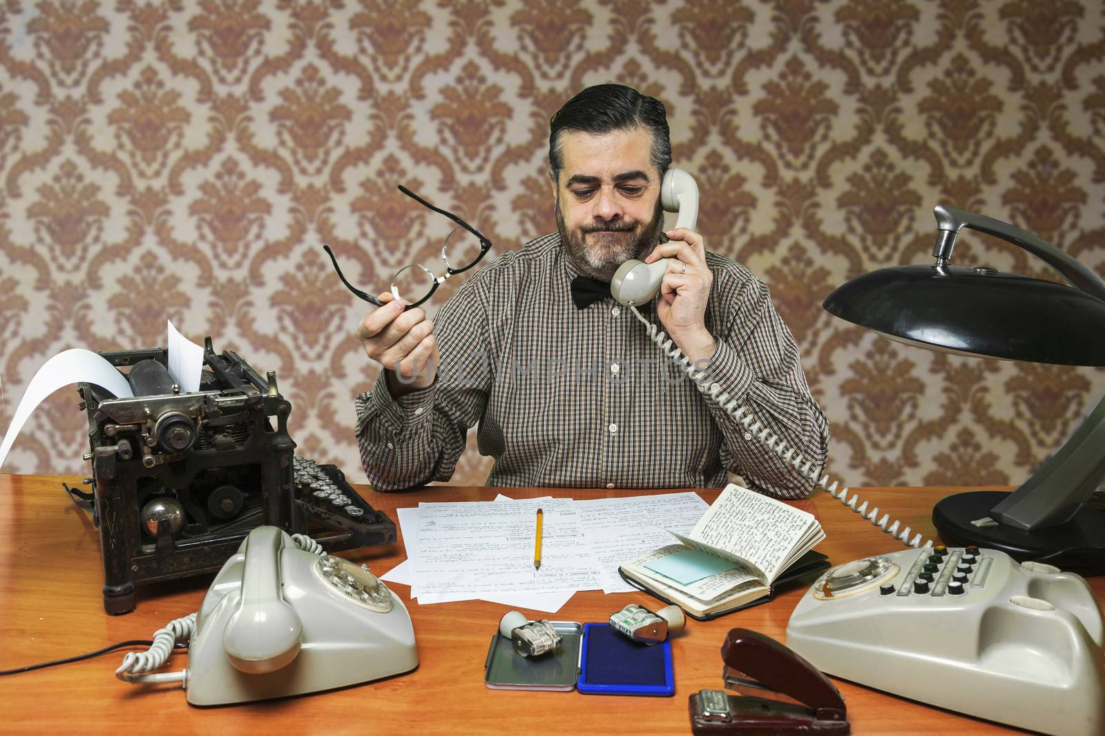 Employee with glasses talking on the phone in the office in the 1960s