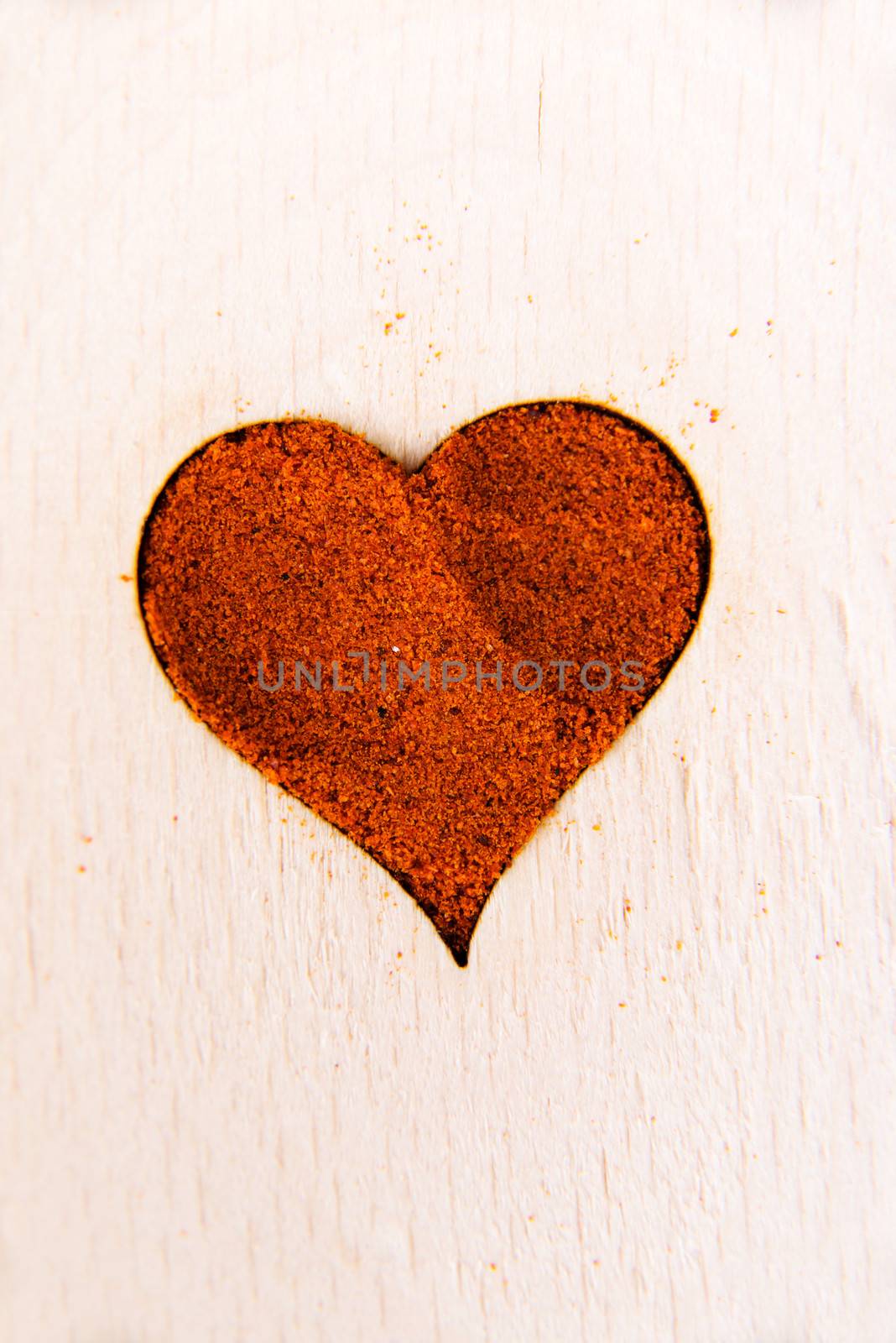 Heart shape made from spice on a wooden spoon. Composition.